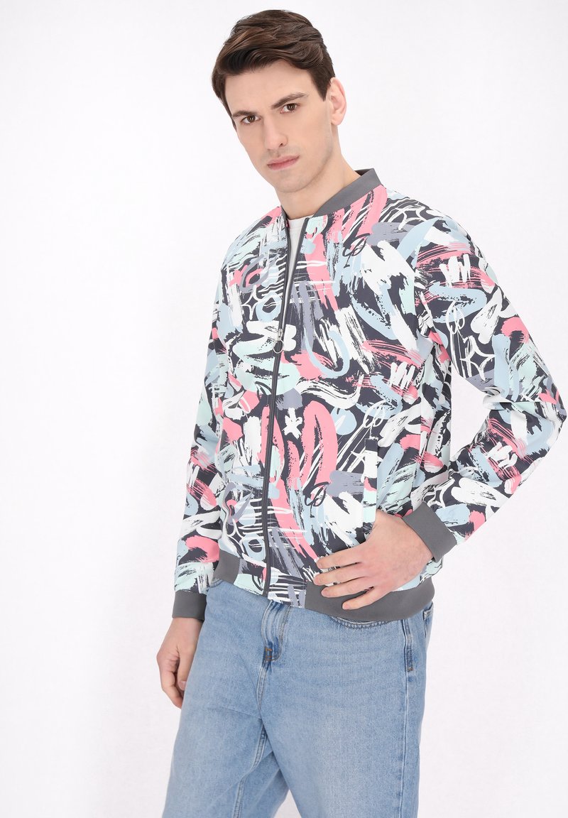 Jachetă bomber colorată, cu un amestec de modele în nuanțe de roz, albastru și gri, având un guler și manșete ribbate gri.