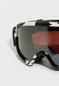 Óculos de esqui com armação padrão em preto e branco e lentes escuras. Apresentam um forro de espuma confortável e uma tira ajustável.