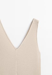 Débardeur beige en tricot sans manches avec un col en V profond et une texture côtelée, présenté à plat sur un fond blanc.