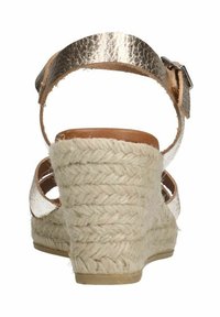 Wedge sandaal met een metallic gouden band en een gevlochten jute hak. De hak is bedekt met een gestructureerde natuurlijke vezel voor grip.