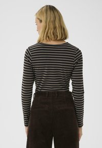 Langærmet skjorte i mørkebrun med fine sorte striber, lavet af blødt stof. Har rund halsudskæring og et slim fit design.