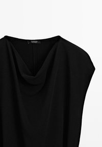 Blusa nera con collo a cowl realizzata in tessuto morbido. Presenta maniche corte e larghe e una lucentezza sottile. Etichetta "Massimo Dutti" visibile al collo.