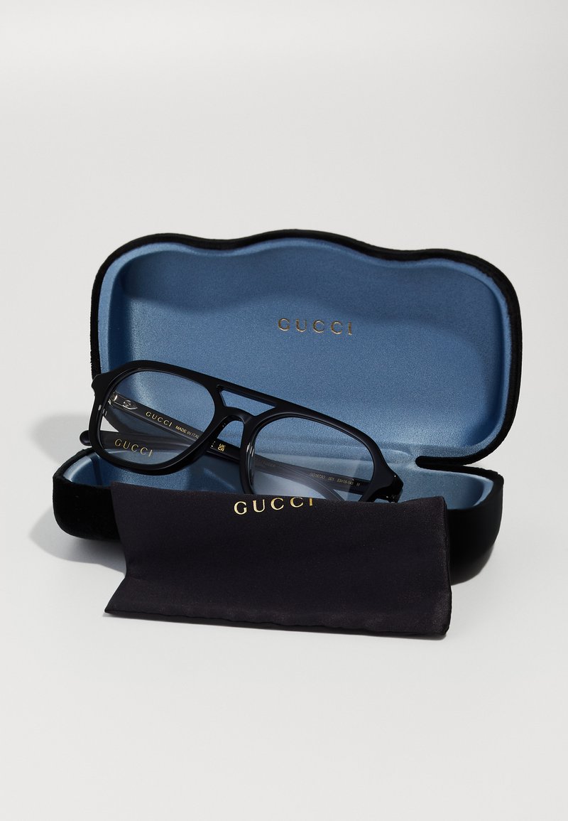 Gucci-bril in een zwarte etui met een blauwe binnenkant. De monturen zijn rechthoekig, zwart met metalen accenten. Inclusief een zwarte reinigingsdoek.