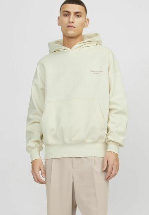 Beige hætte sweatshirt med en kængurulomme, ribbede manchetter og broderet logo. Blødt stof og afslappet pasform, båret med lyse beige bukser.