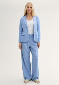 Light blue blazer and matching wide-leg trousers, made from smooth fabric. Features a notch lapel, two buttons, and side pockets.