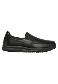 Zapatos negros tipo slip-on con un upper de cuero liso, paneles elásticos en los lados y una suela de goma texturizada que presenta profundas ranuras para mayor tracción.