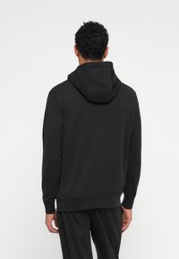 Sweatshirt preto com capuz, de textura suave, mangas longas e punhos canelados. Apresenta um bolso canguru e um corte confortável.