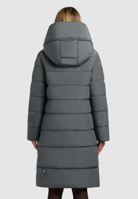 Grå pufferjakke med en stor, struktureret hætte, lodret quiltet tekstur og et logo-patch på nederste venstre side.