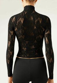 Haut à manches longues en dentelle noire avec un col haut, orné de motifs floraux et d'une silhouette ajustée. Associé à un bas noir.