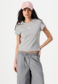 Grå cropped t-shirt med et lille hvidt Adidas-logo, parret med grå vide bukser med snoretræk i taljen og sidelommer.