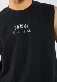 Čierne bezrukávové bavlnené tričko s bielou nebeskou grafikou a textom "CELESTIAL" umiestneným na hrudi. Hladká textúra.