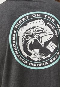 Gray t-shirt featuring a large circular graphic in white and turquoise, depicting a fish and text about performance fishing gear.
