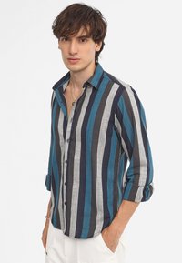 Striped shirt featuring alternating grey, navy, and turquoise lines, button-down design, and rolled-up sleeves. Made of lightweight fabric.