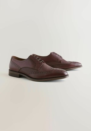 Braune Lederschuhe mit Flügelkappen-Design, perforierten Akzenten und glatter Oberfläche; verfügen über eine Schnürung und einen Holzabsatz.