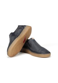 Zapatos tipo slip-on de material de malla azul oscuro con un acabado texturizado. Con una suela de goma beige y acentuaciones de costura. Sin cordones.