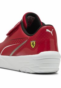 Punane sünteetiline spordijalats siledal pinnal, valge tallaga, hõbedaste aktsentidega ja kollane Ferrari logo küljes. Velcro rihmaga sulgemine.