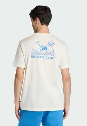 Kremowa bawełniana koszulka z niebieską grafiką przedstawiającą osobę kopiącą piłkę nożną, palmy oraz tekstem „SUMMER KICK OFF” na plecach.