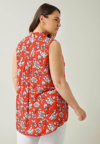 Rote Bluse mit floralem Muster, Kragen, ärmellosem Design, schwarzem Blumenmuster, Rückenfalte und abgerundetem Saum.