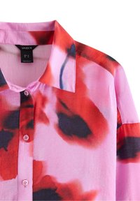 Košile na knoflíky z lehké látky. Má růžový podklad s červenými a černými abstraktními vzory a klasický límec se světle růžovými knoflíky.