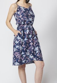 Kukkakuosiset, hihattomat mekot tummansinisinä, joissa on vaaleanpunaisia ja valkoisia kukkia, vyötäröltä kiristetty ja sivutaskut. Pehmeä kangas.