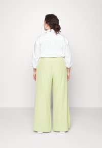 Camisa branca de bot�ões com mangas oversized, combinada com calças largas verde claro. Design simples; tecido suave; minimalismo nos detalhes.