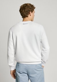 Sudadera blanca con puños y bajo acanalados, que presenta un pequeño logo azul de "London" en la parte posterior del cuello, fabricada en suave material de algodón.