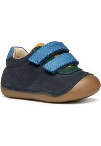Scarpa per bambino in suede navy, con due cinturini in velcro blu, accentuata da tessuti verdi e gialli, caratterizzata da una suola in gomma marrone arrotondata.