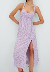 Robe sans manches lilas avec imprimé floral, longueur genoux, corsage froncé et fente sur le côté. Le tissu semble léger avec une texture douce.
