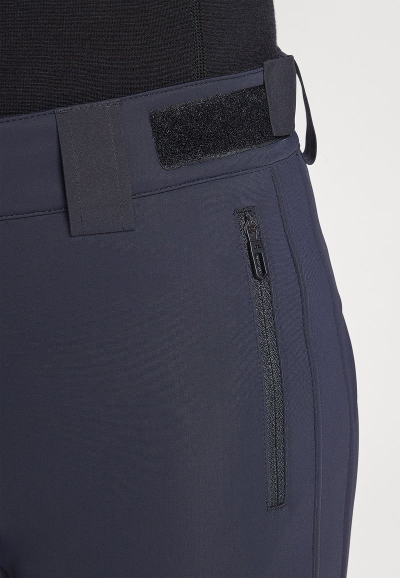 Marineblaue Sporthose mit einem Klettverschlussbund und einer Reißverschlusstasche an der Seite, aus einem glatten, dehnbaren Stoff.