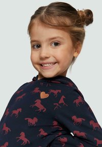 Felpa blu navy con motivi di cavalli rossi e un accento di cuore glitterato. Tessuto morbido con una vestibilità comoda, dotata di tasca a marsupio e cappuccio.