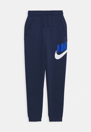 Dunkelblaue Nike Jogginghose mit elastischem Bund, Kordelzug, Seitentaschen und großem blau-weißem Nike-Logo am linken Oberschenkel.