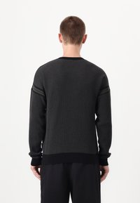 Pulover din tricot texturat negru, cu mâneci lungi, având dungi orizontale închise pe umeri și un guler rotund și un tiv ribat.