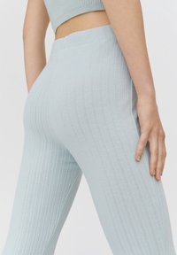 Leggings bleu clair côtelés avec une ceinture sans couture, offrant une coupe ajustée et une texture douce, mettant en valeur des motifs subtils dans le tissu.
