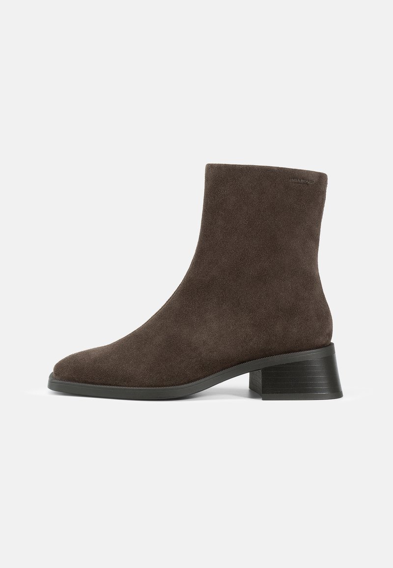 Stivale alla caviglia in suede marrone con punta rotonda, superficie strutturata e tacco spesso, caratterizzato da un design minimalista e senza hardware visibili.