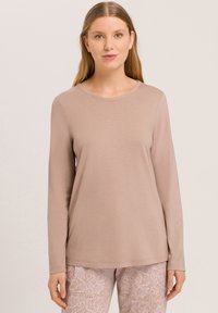 Lichtbruine lange mouw top van zachte stof met een ronde hals en een ontspannen pasvorm, gecombineerd met gemusterde, lichtgekleurde broek.