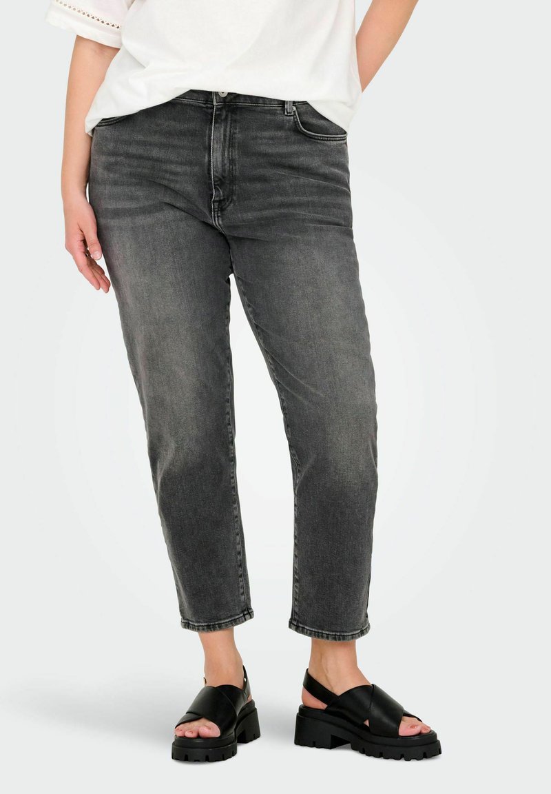 Jeans grigi a gamba dritta con texture sbiadita, cinque tasche e vita a media altezza. Abbinati a sandali neri spessi con cinturini incrociati.