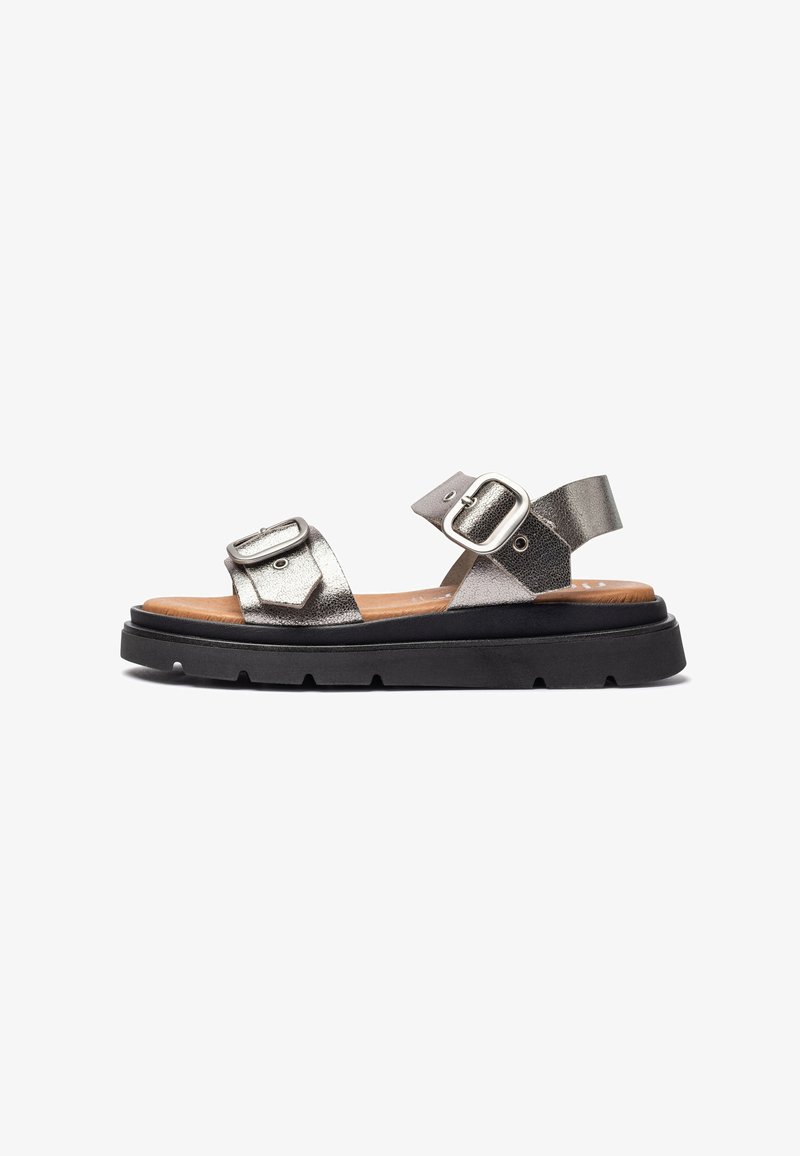 Metallic zilveren leren sandalen met twee verstelbare gespen, zwarte rubberen zool en een gestructureerde voetbed voor comfort. Platte, open teen ontwerp.