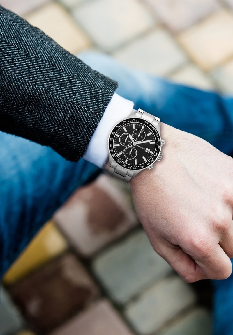 Orologio in metallo argento con quadrante nero, sottodial di cronografo e bracciale in acciaio inossidabile. Il cinturino presenta una finitura spazzolata.