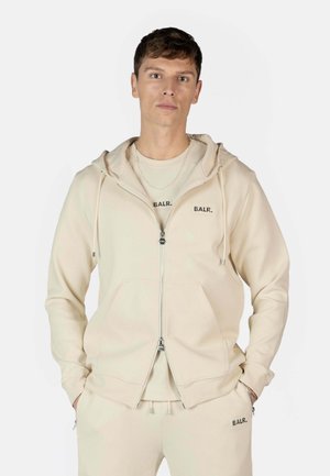 Béžová mikina na zips vyrobená z mäkkého materiálu, s predným vreckom, s logom značky "BALR." na hrudi a uvoľneným strihom.