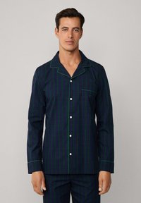 Conjunto de pijama para hombre en un cuadro de tartán de color azul marino oscuro, verde y púrpura. Presenta mangas largas, cuello de muesca, cierre de botones y detalle de bolsillo. Textura de algodón suave.