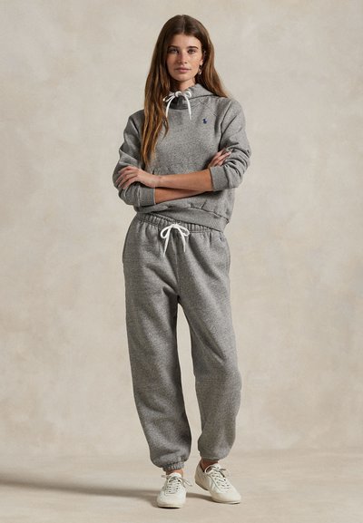 Grijze sweatshirt met capuchon en witte trekkoord, gecombineerd met bijpassende grijze joggingsbroek. Heeft geribbelde manchetten en een klein logoaccent.