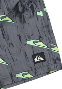 šortky Quiksilver z šedej tkaniny s vlnitým zeleným a žltým vzorom, s čiernym logom na leme. Hladká textúra.