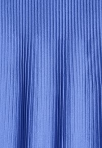 Tissu bleu avec texture côtelée verticale serrée, montrant un fin détail tricoté et des variations subtiles de lumière et d’ombre.