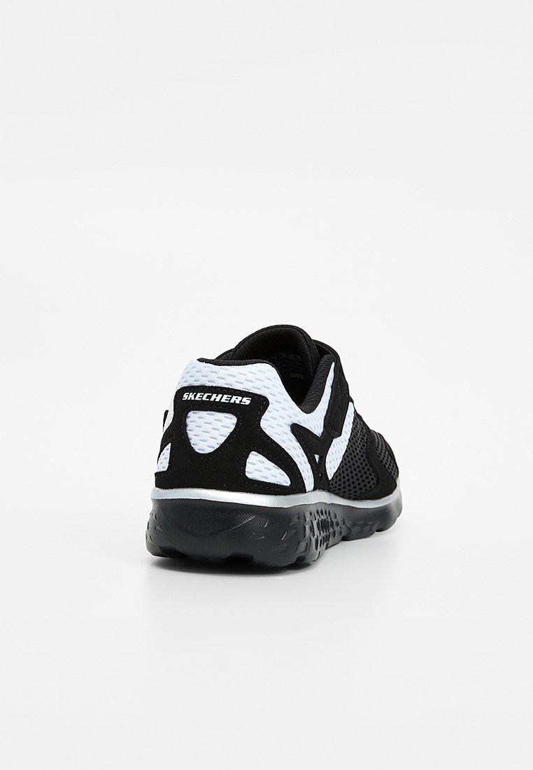 Zapato deportivo Skechers en blanco y negro visto desde atrás, con tela de malla y suela acolchada sobre un fondo blanco.