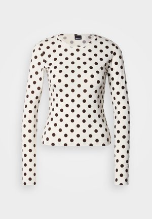 Long-sleeve shirt in cream cotton with a fitted design, featuring large brown polka dots and a rounded neckline.