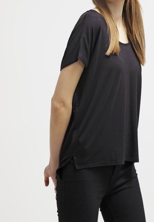 Camiseta negra de manga corta hecha de tela suave, con un ajuste holgado y escote redondeado, con aberturas laterales para mayor comodidad.