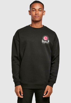 Sort sweatshirt med rund hals, prydet med et pink solgrafik og hvid bølge-design på venstre bryst. Fremstillet af blødt, struktureret stof.