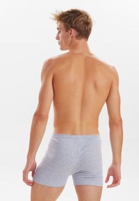 Grå bomulds-boxershorts med en glat tekstur, mellem-høj talje og ingen synlige sømme, vist fra bagsiden mod en hvid baggrund.