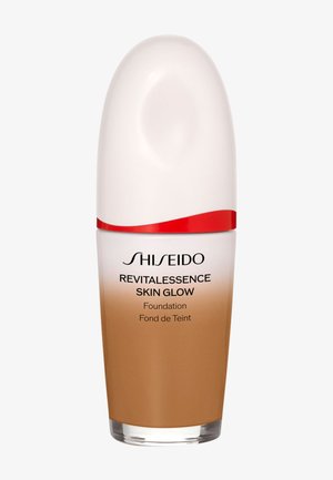 Shiseido Revitalessence Skin Glow flydende foundationflaske med hvid hætte og rød detalje, beige tone synlig i den gennemsigtige nederste halvdel.