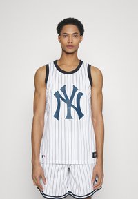 Maglia da basket dei New York Yankees con righe bianche e nere, caratterizzata da un grande logo blu, abbinata a pantaloni corti coordinati e dettagli neri.